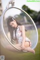 A woman sitting in a bubble chair in a park.