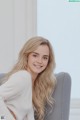 A woman sitting on a gray chair smiling at the camera.