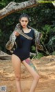 A woman in a black bodysuit holding a large snake.