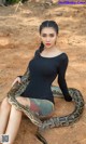 A woman sitting on the ground with a large snake.