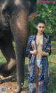 A woman standing next to an elephant in a forest.