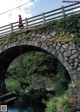 A woman in a red dress standing on a stone bridge.