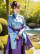 A woman in a blue and purple hanbok standing in front of a pond.