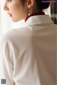 A woman wearing a white shirt and a pair of earrings.