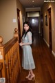 A woman in a blue dress standing on a wooden staircase.