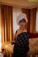 A woman with a towel wrapped around her head standing in a hotel room.